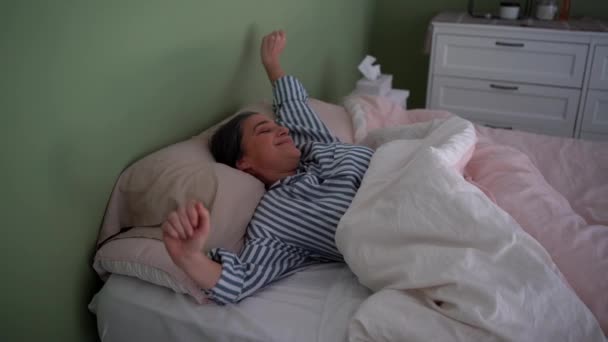 긍정적 여성의 실시간 스트라이프 침실에서 깨어나 머리를 만지고 안경을 입고있는 — 비디오