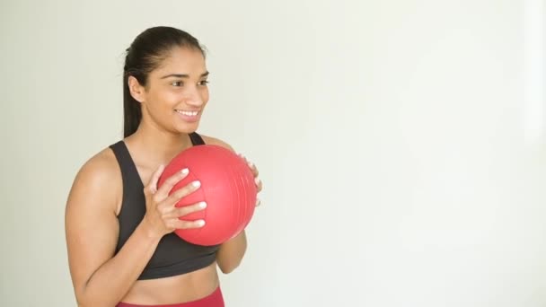 部屋で楽しみにしながらフィットネスボールで働くコンテンツ若いエスニック女性アスリートのサイドビュー — ストック動画