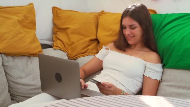 楽しい女性はラップトップでソファに座って 裏庭のテントでオンラインショッピング中にプラスチックカードで購入する — ストック動画