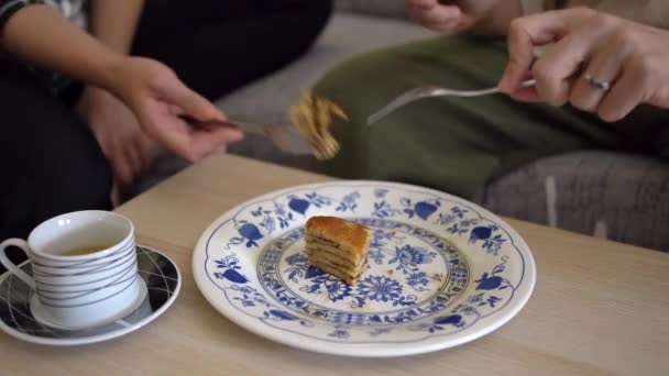 Stock video Cropped unrecognizable couple hands eating homemade pancakes placed on plate with knife and fork