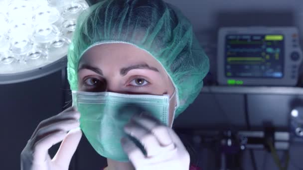 病院で手術を行う前に 医療用マスクと帽子の大人の女性はカメラを見て — ストック動画