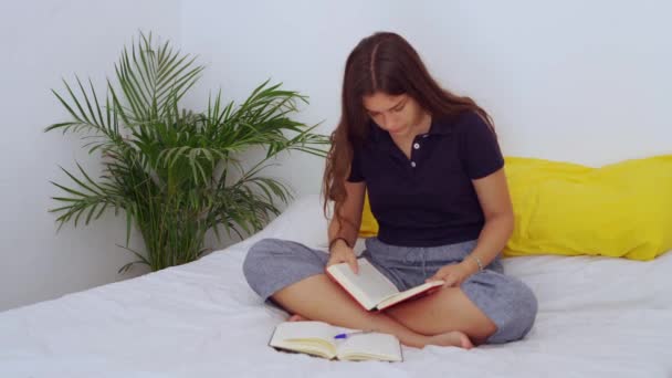 Νεαρή Ξυπόλητη Γυναίκα Που Κάθεται Στο Κρεβάτι Και Διαβάζει Βιβλίο — Αρχείο Βίντεο