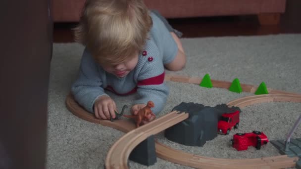 自宅でカーペットの上で恐竜と遊んでかわいい髪の小さな子供 — ストック動画