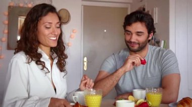 Genç çift kahvaltı yapıyor, romantik oynuyor ve gülüyor. 