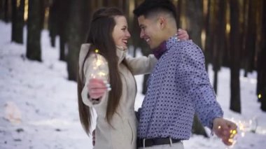 Genç çift kışın karlı ormanda aşık.
