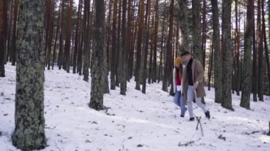 Genç çift kışın karlı ormanda aşık.