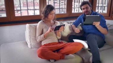 Kanepe üzerinde iki tablet bilgisayarlarla genç Çift