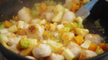 Spatulayla tanınmayan biri evde öğle yemeği hazırlarken lezzetli sebze güveciyle köfteyi karıştırıyor.