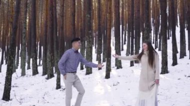 Genç çift kışın karlı ormanda aşık.