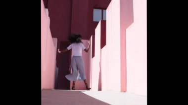 Black woman in a colorful building dancing 