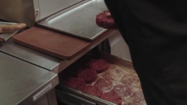  Adam gaz sobasında siyah tavayla hamburger hazırlıyor. Yemek pişirme konsepti.