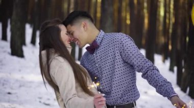 Genç çift kışın karlı ormanda aşık.