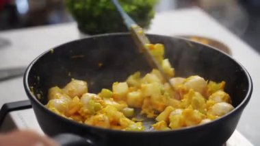 Spatulayla tanınmayan biri evde öğle yemeği hazırlarken lezzetli sebze güveciyle mantarı karıştırıyor.