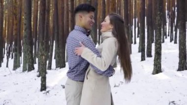 Genç çift kışın karlı ormanda aşık.