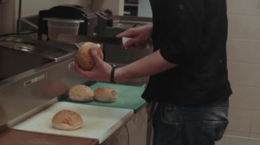 Adam mutfakta hamburgerlere ekmek hazırlıyor..