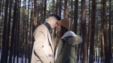 Genç çift kışın karlı ormanda aşık.