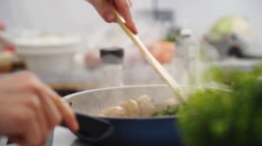 Spatulayla tanınmayan biri evde öğle yemeği hazırlarken lezzetli sebze güveciyle mantarı karıştırıyor.