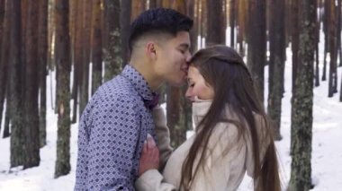 Genç çift kışın karlı ormanda aşık.