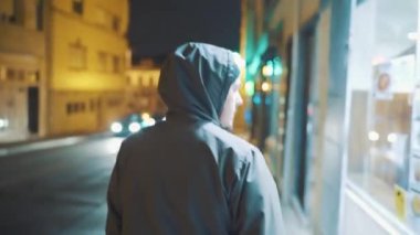 Geceleri sokakta yürüyen kapüşonlu bir adam.