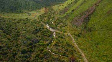 Yeşil tepeler arasında kıvrılan nehir ve yol