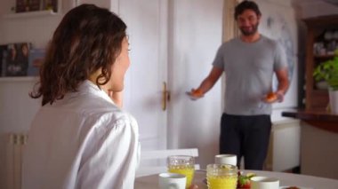 Genç çift kahvaltı yapıyor, romantik oynuyor ve gülüyor.