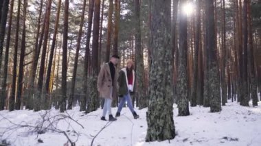 Genç çift kışın karlı ormanda aşık.