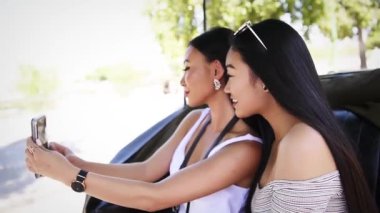 Çekici esmer Çinli turist kızlar selfie çekiyorlar Sevilla, İspanya 'da arabada oturuyorlar.