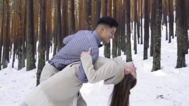 Genç çift kışın karlı ormanda aşık.