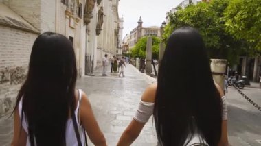 İspanya, Sevilla 'da Katedral' in yanında el ele tutuşurken gülümseyen iki Çinli kız..