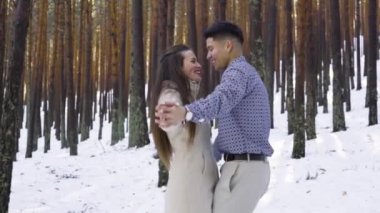 Genç çift kışın karlı ormanda aşık.