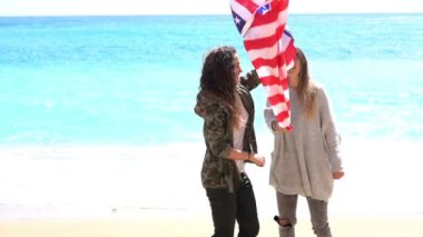 Sahilde Amerikan bayrağı taşıyan güzel genç kadınlar.