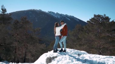 Genç çift kışın karlı ormanda aşık.