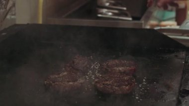 Benzin ocağında siyah tavalı hamburgerlerin yakın çekimi. Yemek pişirme konsepti.