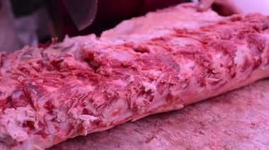 Kasap dükkanında bir parça et kesiyor.