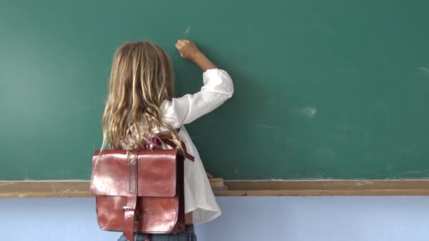 教室の机に鉛筆で座って執筆する若い生徒の女の子のことを考える — ストック動画