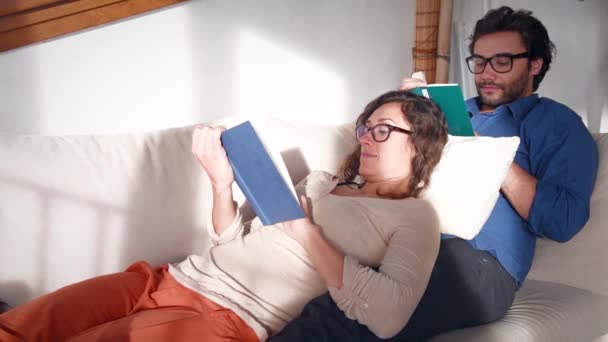 Pareja Joven Leyendo Libros Abrazándose Sofá — Vídeo de stock