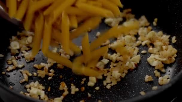 Wysoki Kąt Gotowania Wprowadzenie Surowego Makaronu Penne Gorącej Patelni Czosnku — Wideo stockowe