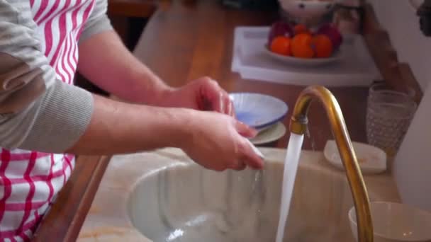 台所の若い男が皿を洗っている — ストック動画
