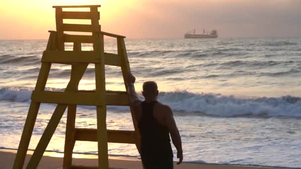 Sylwetka Przystojnego Młodego Mięśniaka Wybrzeżu Podczas Zachodu Słońca — Wideo stockowe