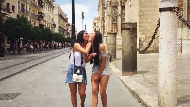 西班牙塞维利亚大教堂附近的街道上 两个中国女孩笑着走路 — 图库视频影像