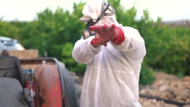 유기농 농장에서 트랙터에있는 농약과 나무에 살충제를 준비하는 보호복과 마스크를 착용하는 — 비디오