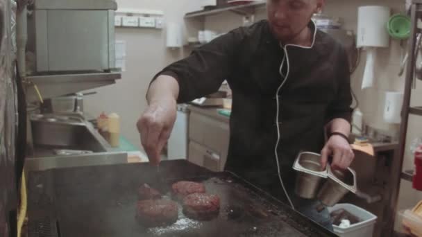 Een Man Die Hamburgers Met Een Zwarte Pan Een Gasfornuis — Stockvideo