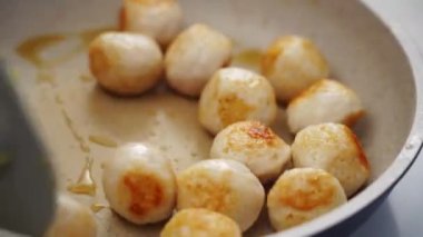 Evde öğle yemeği hazırlarken köfteleri kızartma tavasına koyan isimsiz kişinin üst görüntüsü.