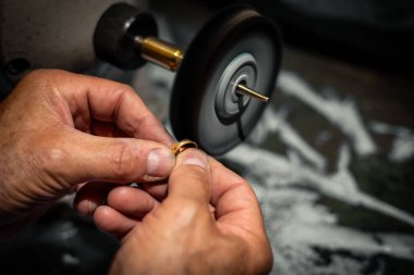 Goldsmith mücevher atölyesinde altın yüzük parlatıyor. J