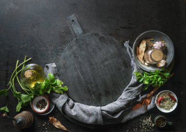 Mutfak aromalı ve baharatlı mutfak aletleri boş siyah kesme tahtasının etrafında. Üst Manzara. Çerçeve
