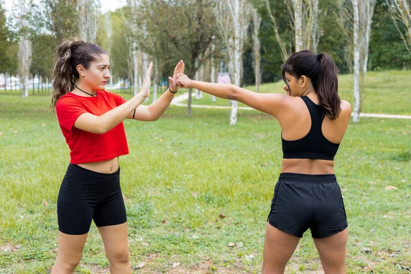 Two young multiethnic female boxers training outdoors. Boxing sparring and punching workout in a city park.