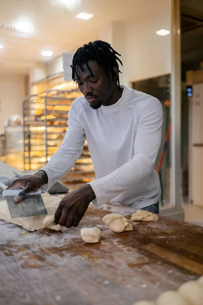 Young Black Baker Dreadlocks White Clothes Cutting Dough Scapula Bakery — Stock Photo, Image