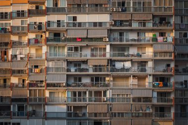 Gündoğumunda modern apartman bloğunun dışında eşyalarla ve kuru giysilerle balkonlar.