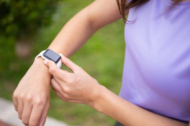 Şehir parkında antrenmanı izlemek için spor takip cihazı takan bir kadın. Sağlık, sağlık ve aktif yaşam tarzı.