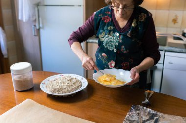 Ev yapımı mutfakta kroketleri kaplamak için kıdemli kadın yumurta çırpıyor.